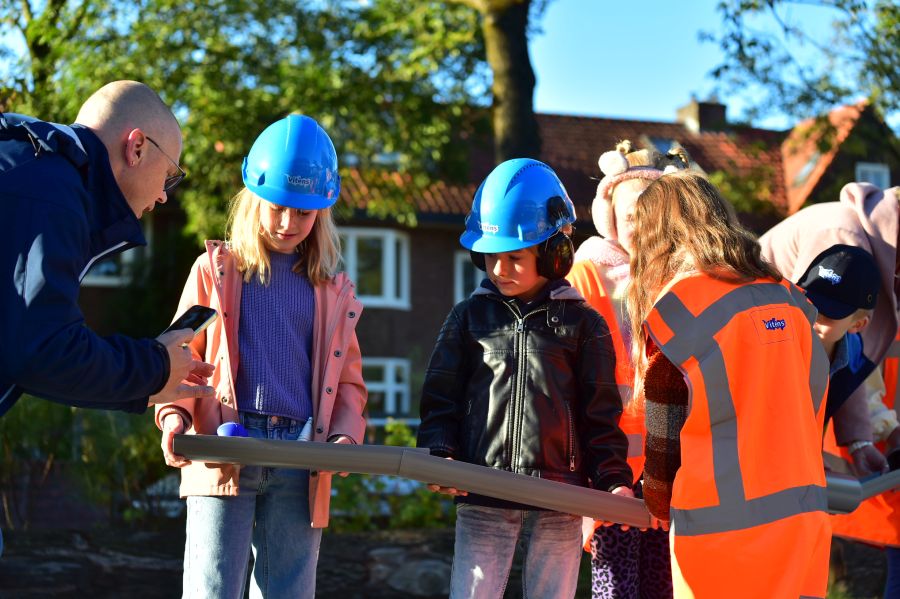 Kinderen die via een waterleiding een bal naar de overkant proberen te brengen