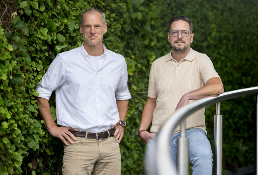 Foto van 2 mannen voor een groene achtergrond