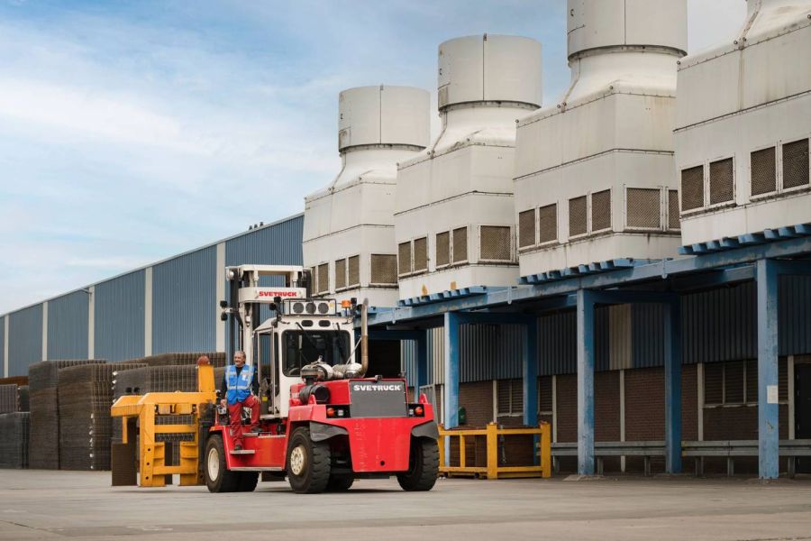 Een man op een heftruck voor een fabriek